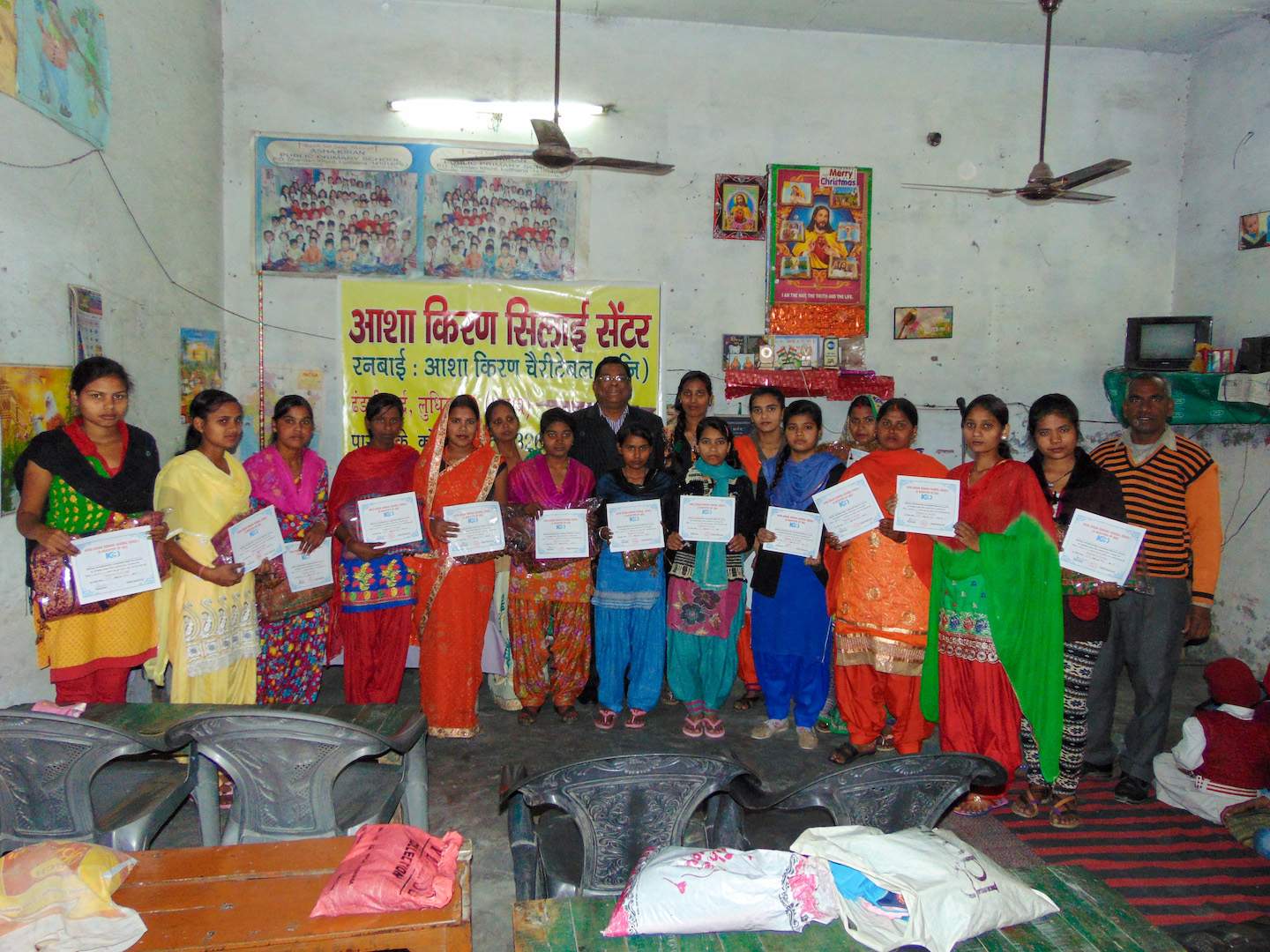 A group of women display their certificates after completing their sewing course and learning to manage money.